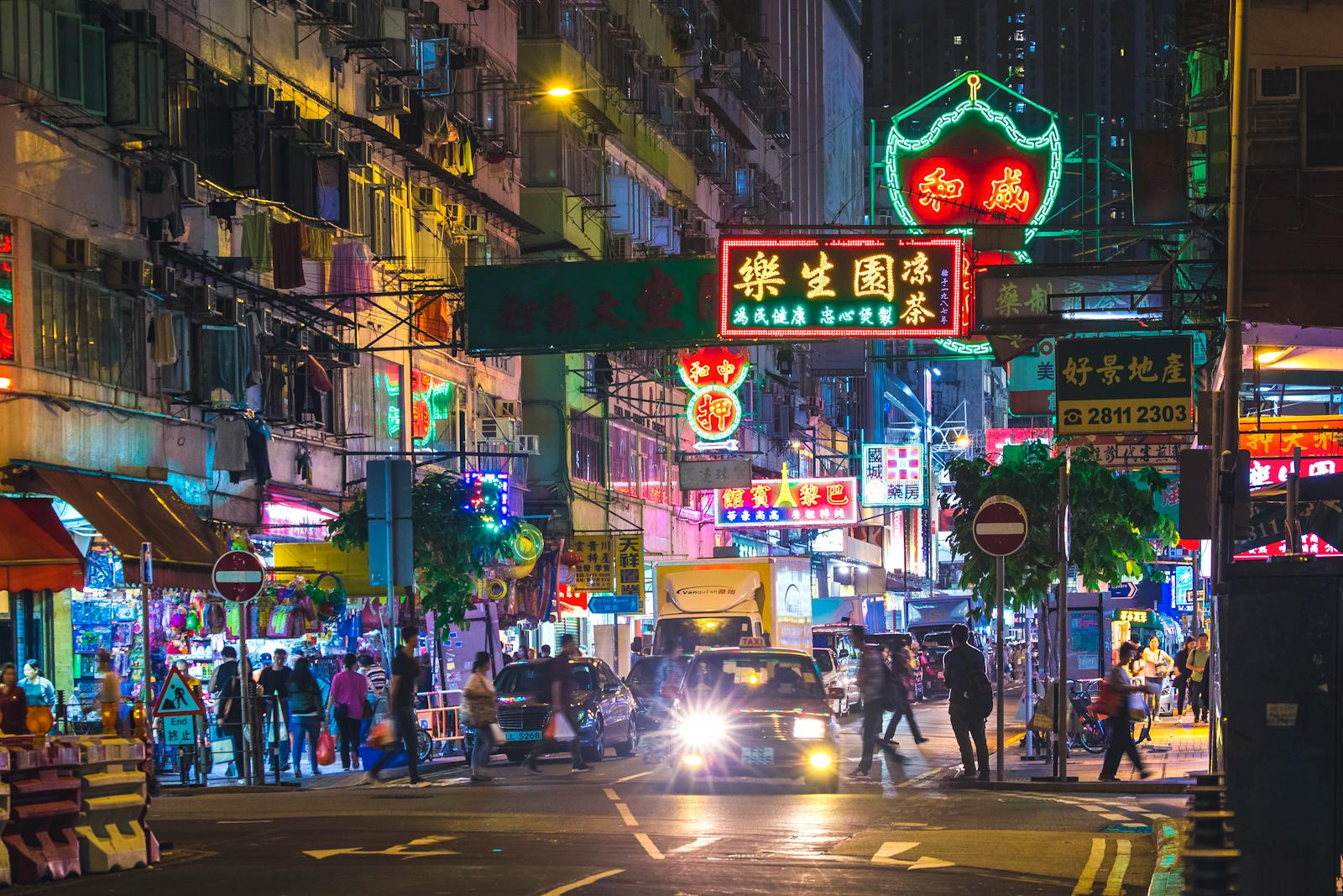 Colorful neon lights illuminate a bustling street in the New Territories, Hong Kong, by night.