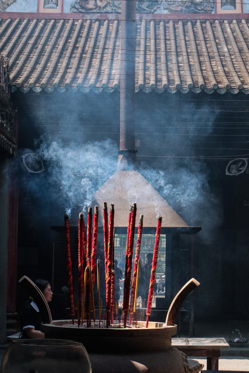 Ambient smoke rises from burning incense sticks in a traditional Chinese temple setting, creating a serene atmosphere.