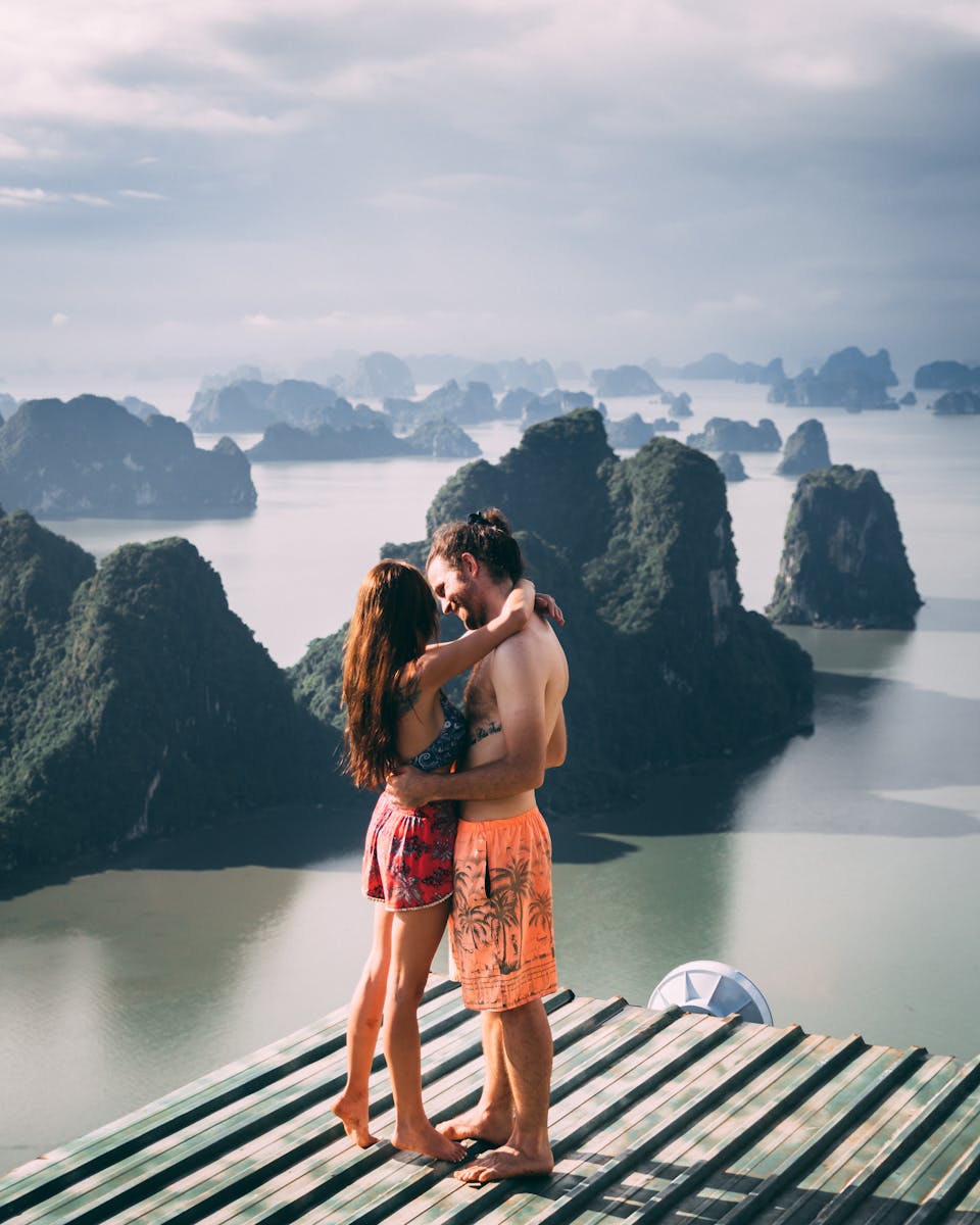 A couple shares a romantic embrace with a stunning view of Halong Bay's limestone islands.