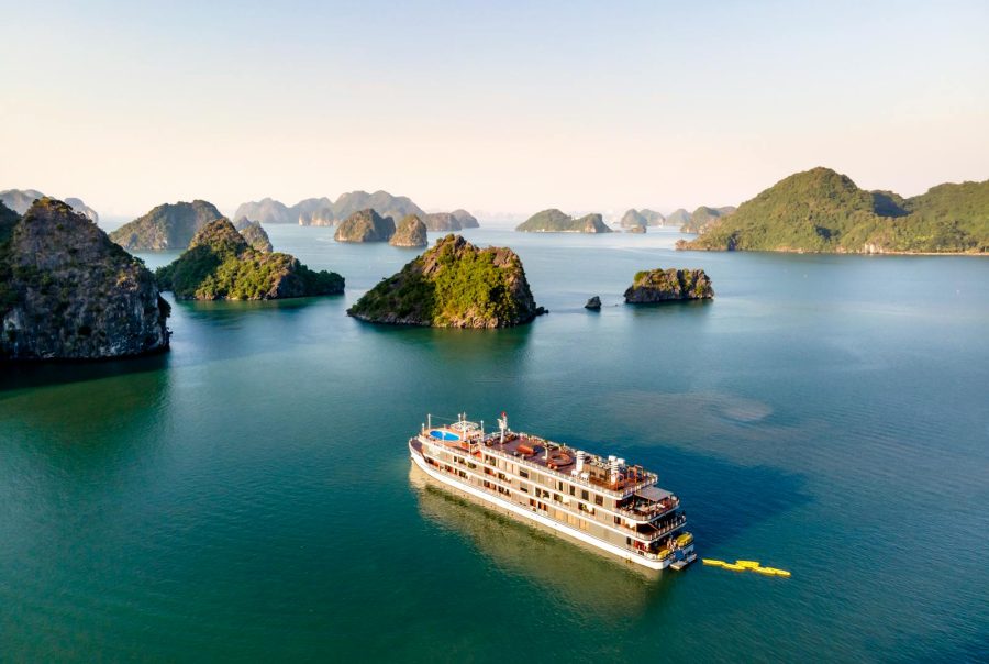Aerial view of a cruise ship navigating through Halong Bay, featuring scenic limestone islands and calm waters.