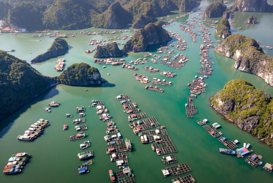 Stunning aerial view of floating villages amidst limestone islands in a serene green bay.