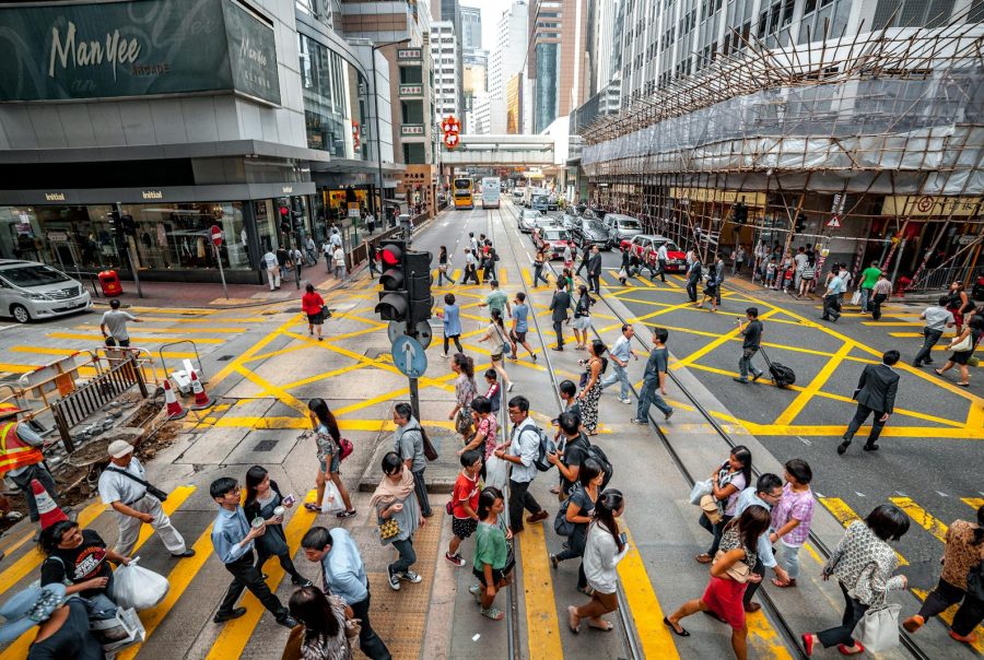 A vibrant street scene in Hong Kong showing a busy pedestrian crossing with many people and urban architecture.