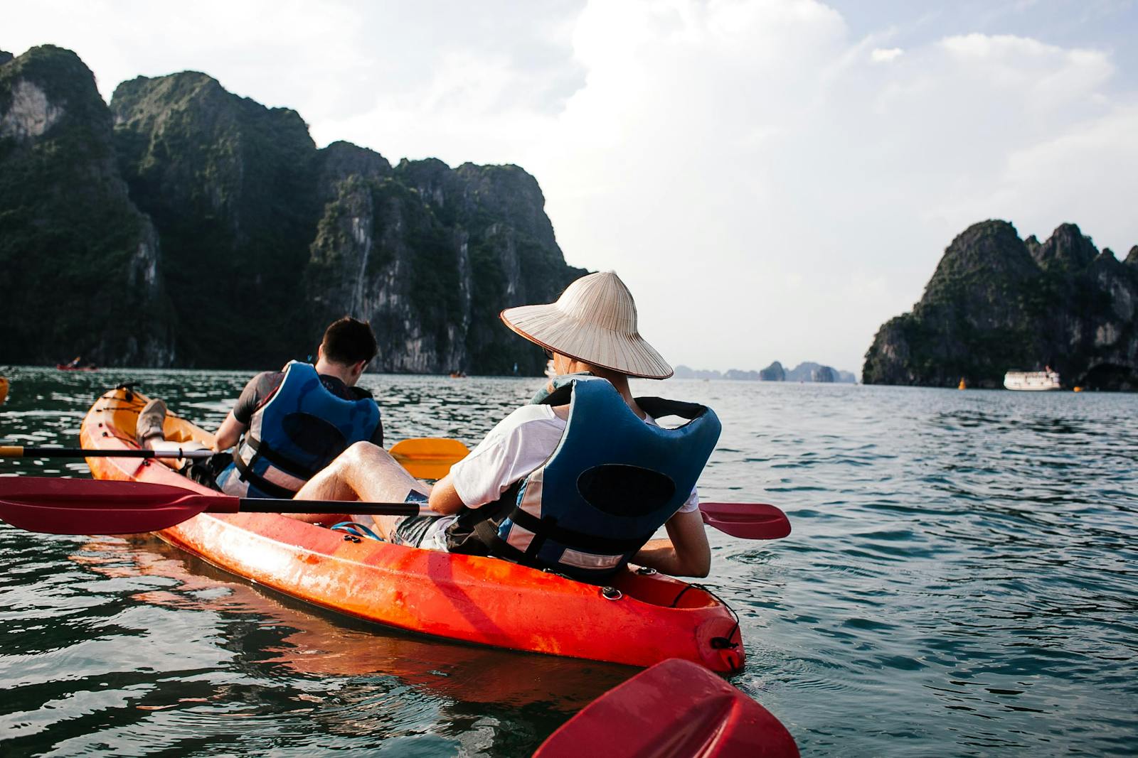 Tourists kayaking in Halong Bay, Vietnam under clear skies, enjoying summer adventure.