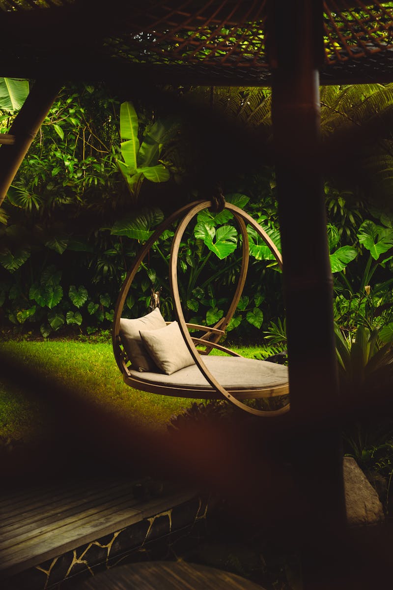 Elegant hanging chair amidst vibrant tropical greenery in a serene garden setting.