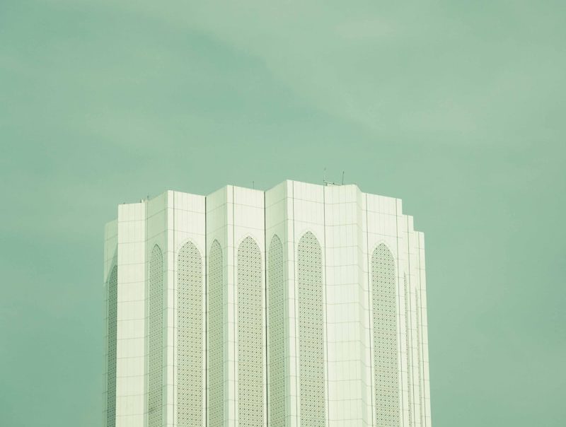 A tall, white building is beneath a cloudy sky.
